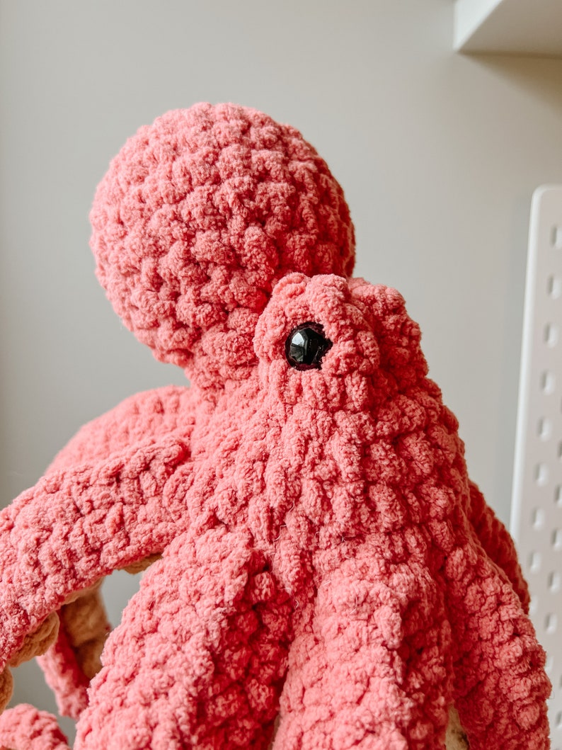May include: A pink crocheted octopus plush toy with black eyes.