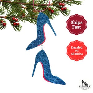 Può includere: Ciondolo natalizio a forma di scarpa con tacco alto blu glitter con bordino rosso glitter. Il ciondolo è appeso a un ramo di pino.