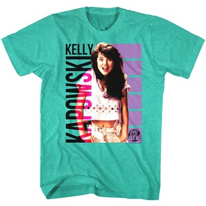 May include: A teal blue t-shirt with a graphic of Kelly Kapowski from the TV show Saved by the Bell. The graphic is in pink and black and features Kelly's name and a striped background.