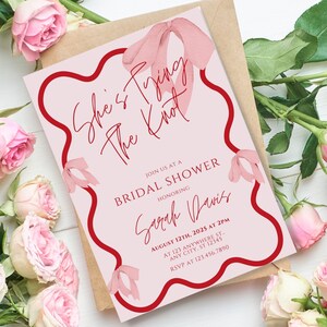 May include: Pink bridal shower invitation with a red border and a watercolour bow. The text reads "She's Trying The Knot" and includes the bride's name, date, time, and RSVP information.