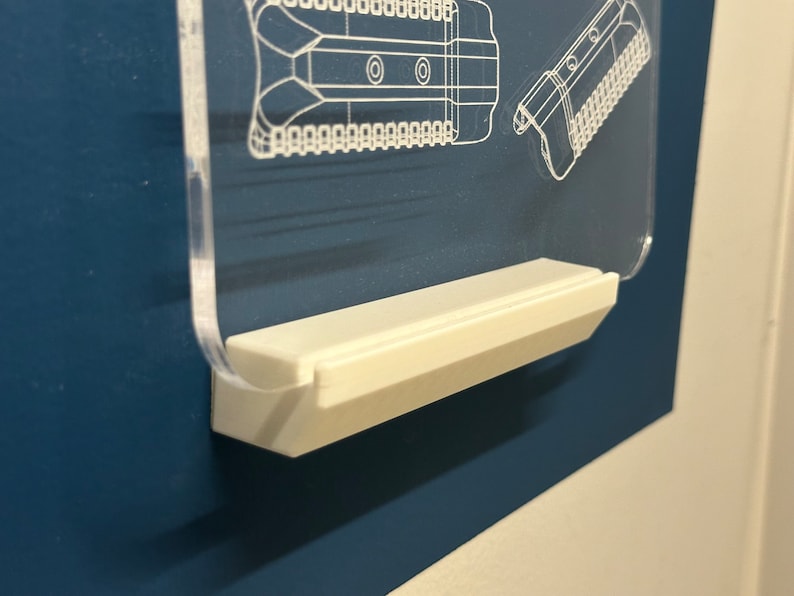 Puede incluir: Un expositor de acr&iacute;lico transparente con una base de pl&aacute;stico blanco. El expositor est&aacute; dise&ntilde;ado para sostener un objeto peque&ntilde;o, como una figurita o una joya.