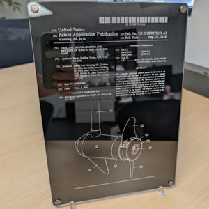 May include: A rectangular black plaque featuring a white United States Patent Application Publication for a trolling motor adaptor. The document includes technical text, a patent number, and a detailed line drawing of a motor component with labels.