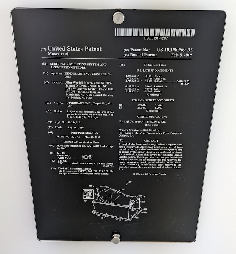 May include: A black rectangular plaque displaying the United States Patent US 10,198,969 B2 for a surgical simulation system and associated methods. The document includes technical text, patent details, and a line drawing of a simulation device.