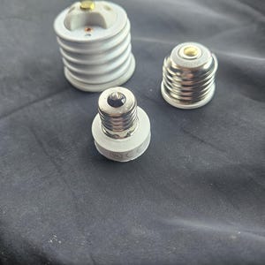 May include: Three different types of light bulb sockets. Two are white ceramic and one is silver metal.