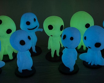 May include: A collection of glowing figurines in various poses. The figures have rounded bodies, black eyes, and are illuminated in shades of blue and green. Each figure is mounted on a small, round black base.