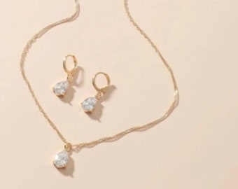 May include: A gold necklace and earrings set with teardrop-shaped clear crystal accents.