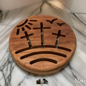 May include: A round wooden wall hanging with a carved design of a sun, three trees, and birds. The design is cut out of the wood, creating a negative space effect.