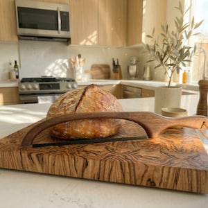 May include: A white ceramic mug with a black handle and the text "But First, Coffee" in a handwritten style. The mug is on a white surface. The mug is approximately 4 inches tall.