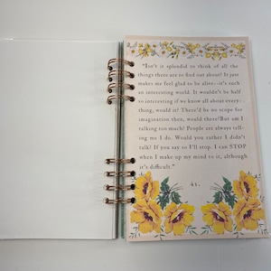 May include: Open notebook with a bronze spiral binding. The right page features text and yellow floral illustrations. The left page is blank. The text includes the phrase, "Isn't it splendid to think of all the things there are to find out about?"