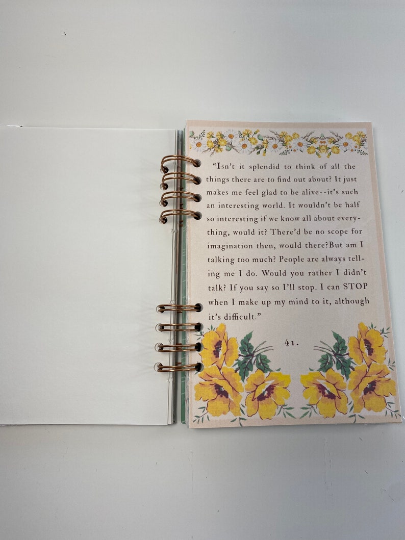 May include: Open notebook with a bronze spiral binding. The right page features text and yellow floral illustrations. The left page is blank. The text includes the phrase, "Isn't it splendid to think of all the things there are to find out about?"