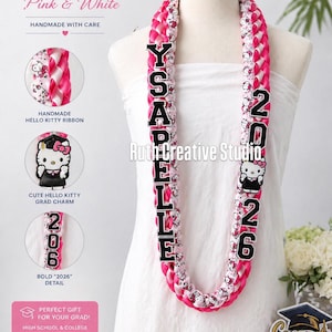 May include: A pink and white Hello Kitty graduation lei with the name "YSABELLE" and the year "2026" in bold black letters. The lei features Hello Kitty ribbon and a cute Hello Kitty grad charm. The text "Graduation Hello Kitty Pink & White" is at the top.