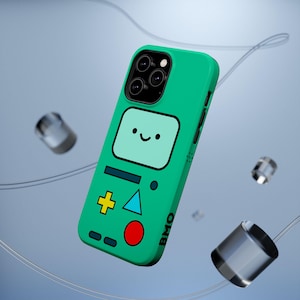 May include: A bright green smartphone case featuring a graphic of a character with a light blue screen face, a yellow plus sign, a blue triangle, a red circle, and the text BMO printed in black on the side, with a triple camera cutout.