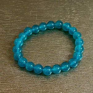 May include: A turquoise blue beaded bracelet with round beads.