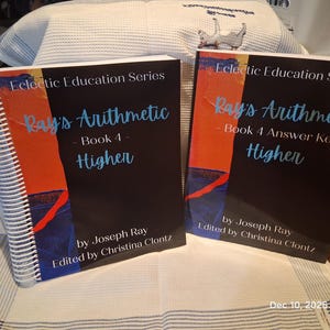 May include: Two books from the "Eclectic Education Series" are displayed. The books are titled "Ray's Arithmetic Book 4 Higher" and "Ray's Arithmetic Book 4 Answer Key Higher". The covers are black with orange, blue, and white accents. The author is Joseph Ray, edited by Christina Clontz.
