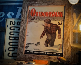 May include: A vintage framed magazine cover featuring a man ice fishing. The cover is for the February 1940 issue of "The Outdoorsman" magazine. The text "Hunter Trader Trapper" is printed above the title. The cover features a man in a red and black plaid shirt and brown pants, holding a fishing rod and looking at a fish on the end of his line. The cover is set against a snowy winter scene.