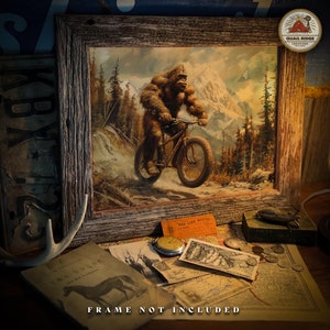 May include: A framed illustration of a Bigfoot riding a bicycle through a snowy mountain landscape. The frame is made of rustic wood and has a distressed finish. The illustration is in a vintage style and features a colorful palette of greens, browns, and blues. The text "Quail Ridge Creations" is visible in the upper right corner of the image.