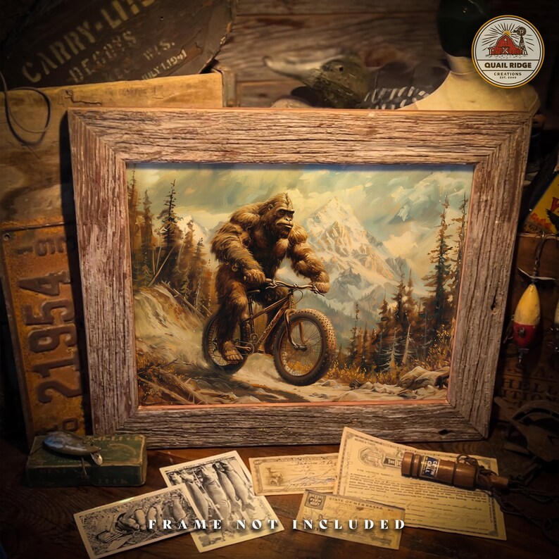 May include: A framed illustration of a Bigfoot riding a bicycle through a snowy mountain landscape. The illustration is in a rustic wooden frame.