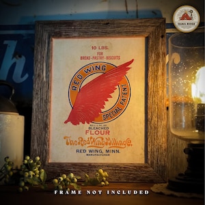 May include: Framed vintage Red Wing Flour advertisement. The print features a red wing graphic on an orange circle, with text indicating 10 lbs. of bleached flour. The frame is rustic wood, and the text "FRAME NOT INCLUDED" is at the bottom.