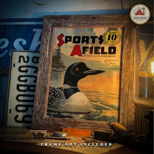 May include: A vintage framed print of a magazine cover for "Sports Afield" magazine, featuring a loon swimming in a lake. The cover is dated September 1934 and has a price of 10 cents. The frame is not included.