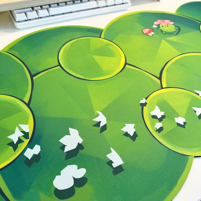 May include: Green and white mousepad with a geometric pattern and a cartoon character with a mushroom and flower.