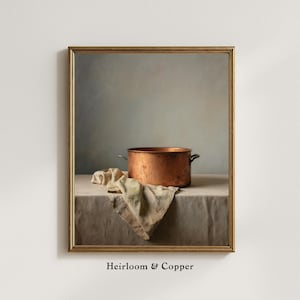 May include: A framed still life print featuring a copper pot with handles, resting on a neutral-toned tablecloth. A beige cloth is draped near the pot. The words "Heirloom & Copper" are printed at the bottom.