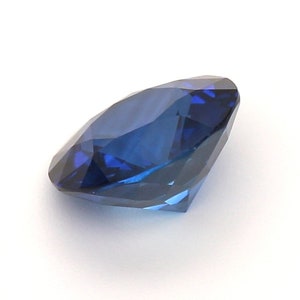 May include: A deep blue sapphire gemstone with a round cut and many facets.