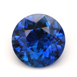 May include: A round, deep blue sapphire gemstone with a faceted cut.