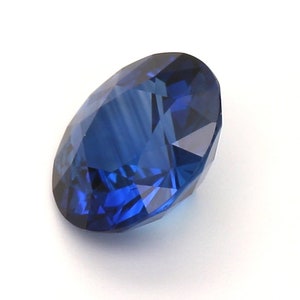 May include: A deep blue sapphire gemstone with a round cut and a faceted design.