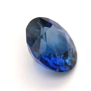 May include: A deep blue oval sapphire gemstone with a faceted cut.
