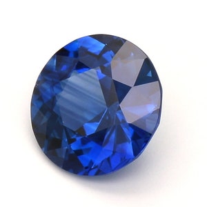 May include: A deep blue sapphire gemstone with a round cut and a faceted design.