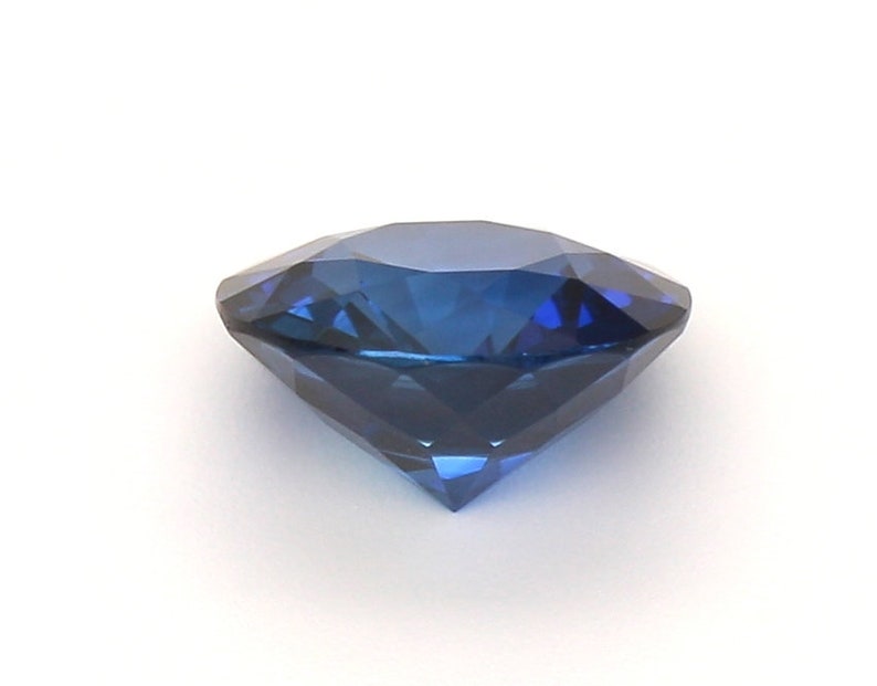 May include: A deep blue gemstone with a round cut and many facets.