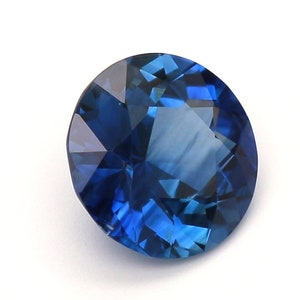 May include: A deep blue sapphire gemstone with a round cut and a faceted design.