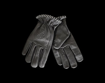 May include: A pair of black leather gloves with white stitching. The gloves have a logo on the back of the left hand.