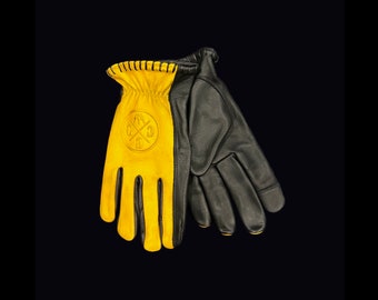 May include: A pair of leather gloves, one yellow and one black. The yellow glove has a cross with a circle around it on the back of the hand.