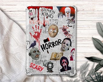 May include: A clear tablet case decorated with horror-themed stickers. The stickers include images of a ghost, a handprint, a crow, a zombie head, a Jason Voorhees mask, and the word "HORROR". The case is on a white surface.