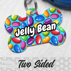 May include: A blue bone-shaped dog tag with a colorful jelly bean pattern and the text "Jelly Bean".