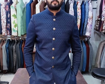 May include: A dark blue blazer with a quilted pattern and gold buttons. The blazer has a mandarin collar and long sleeves. The blazer is displayed in a shop with other blazers on hangers.