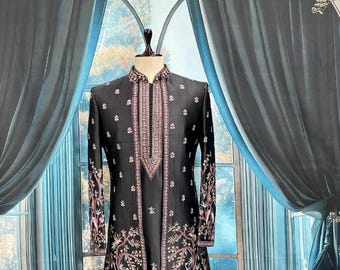 Puede incluir: Una chaqueta formal negra bordada con cuello mandarín. La chaqueta presenta intrincados patrones florales y geométricos en tonos rosa y morado. Las mangas largas y el panel frontal están adornados con bordados detallados.
