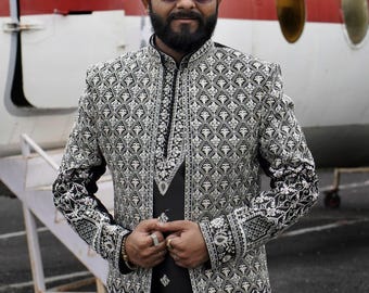 Puede incluir: Una chaqueta negra y plateada con estampado, cuello alto y mangas largas. La chaqueta tiene un diseño geométrico con bordados plateados.