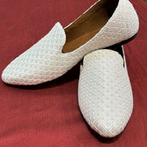 Pode incluir: Um par de mocassins brancos bordados com bico fino. Os mocassins t&ecirc;m um design texturizado e tecido e s&atilde;o feitos de um tecido macio e respir&aacute;vel.