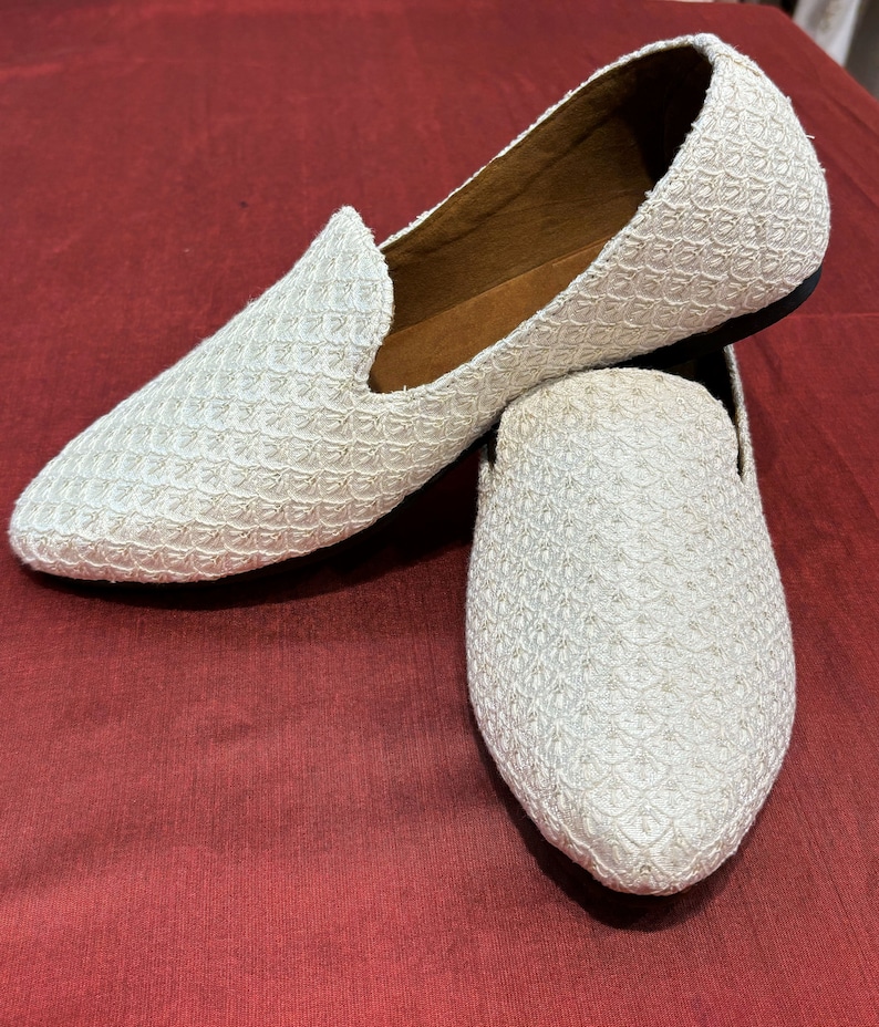 Pode incluir: Um par de mocassins brancos bordados com bico fino. Os mocassins t&ecirc;m um design texturizado e tecido e s&atilde;o feitos de um tecido macio e respir&aacute;vel.