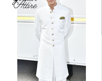 Könnte beinhalten: Ein Mann trägt eine weiße, langärmelige Kurta mit einem Mandarinkragen und goldenen Knöpfen. Er trägt auch weiße Shalwar-Hosen und braune Lederschuhe. Der Text "Golden Attire" ist in schwarzer Kursivschrift auf dem Bild geschrieben.