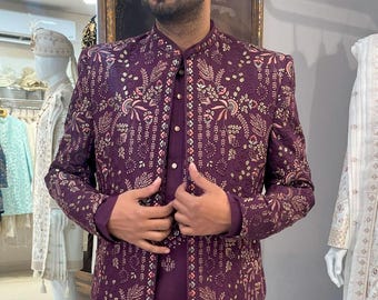 Puede incluir: Una kurta de manga larga, de color morado, con un patrón floral y bordados dorados. La kurta tiene un cuello mandarín y un cierre de botón.