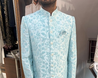 May include: A light blue patterned long-sleeved jacket with a mandarin collar and button closure. The jacket has a floral design and is made of a silky fabric.