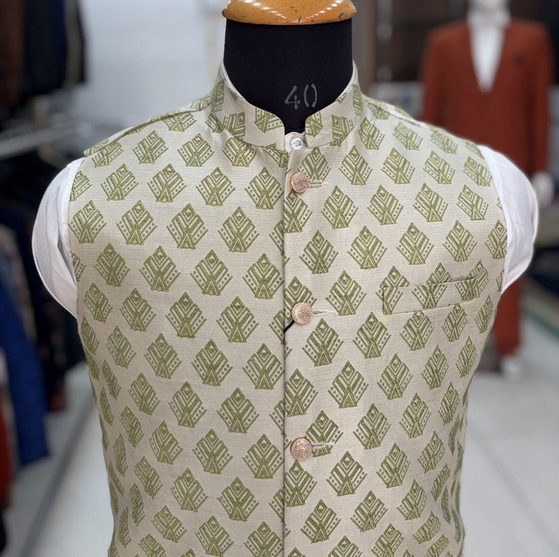 May include: A beige waistcoat with a green geometric pattern and five gold buttons. The waistcoat has a mandarin collar.