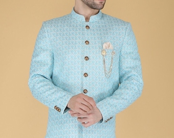 May include: A light blue blazer with a white and light blue patterned design. The blazer has a mandarin collar and a button closure. A gold chain and pin are attached to the pocket.