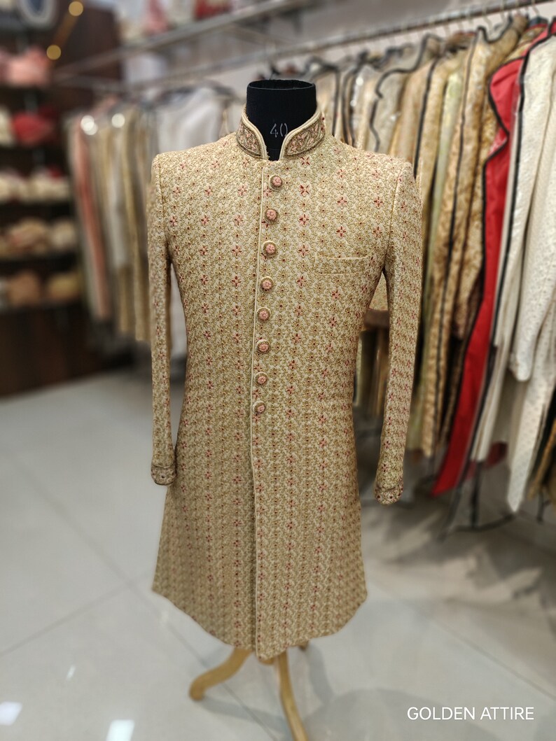 May include: A gold embroidered men's sherwani with a high collar and button closure. The sherwani has a floral pattern and is displayed on a mannequin.