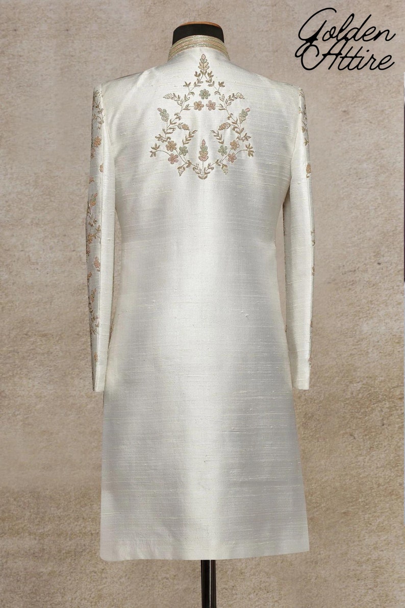 K&ouml;nnte beinhalten: Eine wei&szlig;e, lang&auml;rmelige Kurta mit einem floralen Stickmuster auf der R&uuml;ckseite. Die Kurta ist aus einem glatten, seidenartigen Stoff gefertigt.