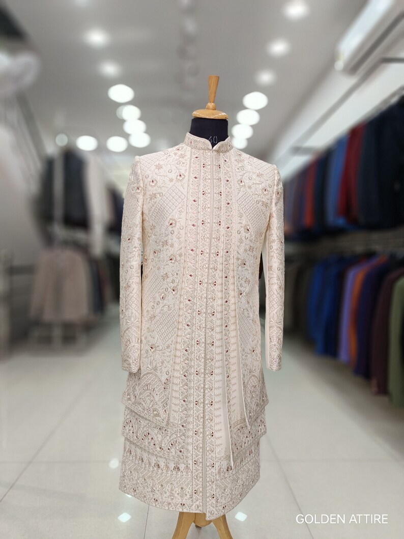 Puede incluir: Una kurta blanca bordada para hombre con cuello alto y detalles intrincados. La kurta est&aacute; en un maniqu&iacute; y tiene un dise&ntilde;o largo y fluido. La tela es un material ligero y transparente. La kurta es una prenda tradicional india.