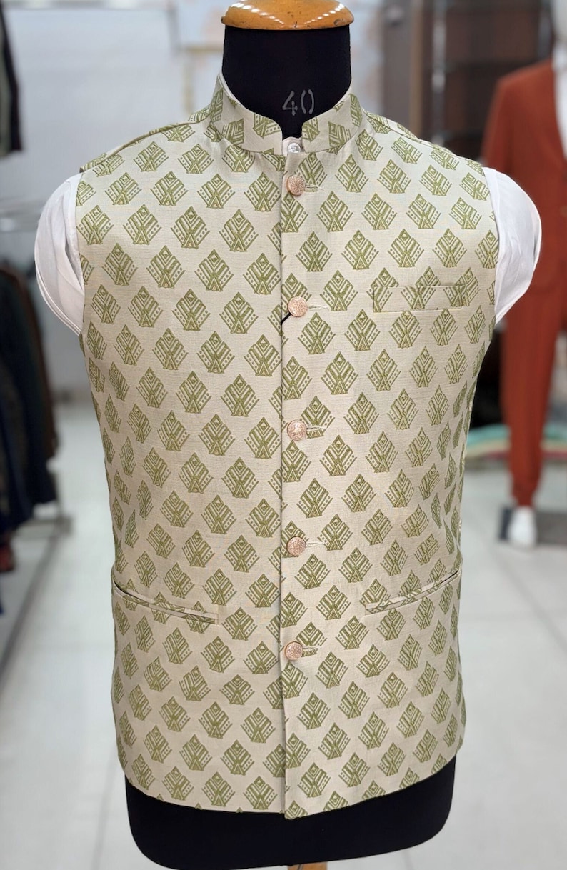 May include: A beige waistcoat with a green geometric pattern and five buttons. The waistcoat has a mandarin collar and two pockets.